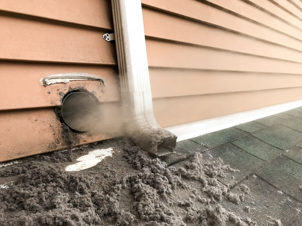 Dirty dry vent spewing lint on outside of house